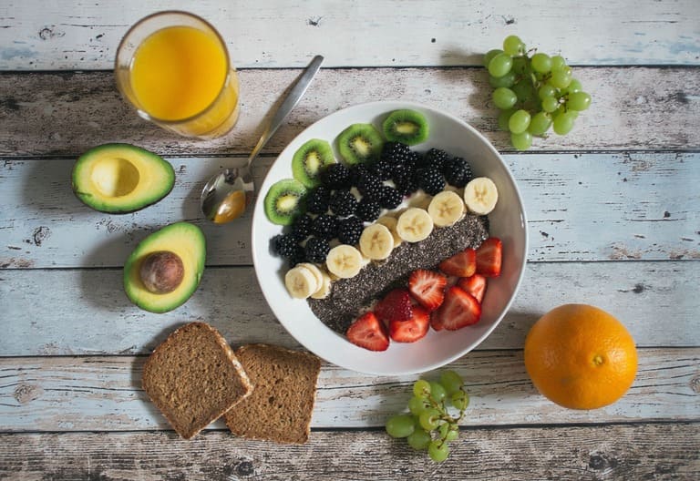 Bol de fruits frais colorés avec avocat et jus d'orange, évoquant une alimentation saine, équilibrée et bienveillante pour la gestion du poids
