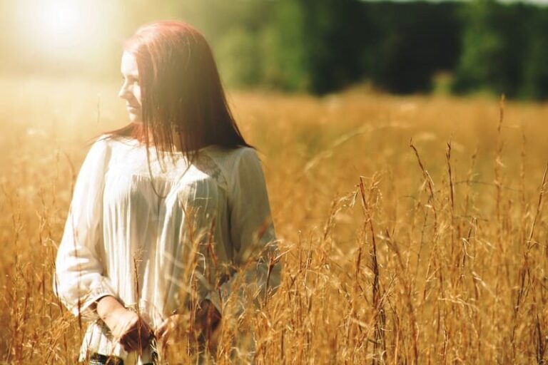 Femme sereine en robe blanche dans un champ doré, évoquant l'apaisement et la transformation de la colère grâce à l'hypnose et la sophrologie