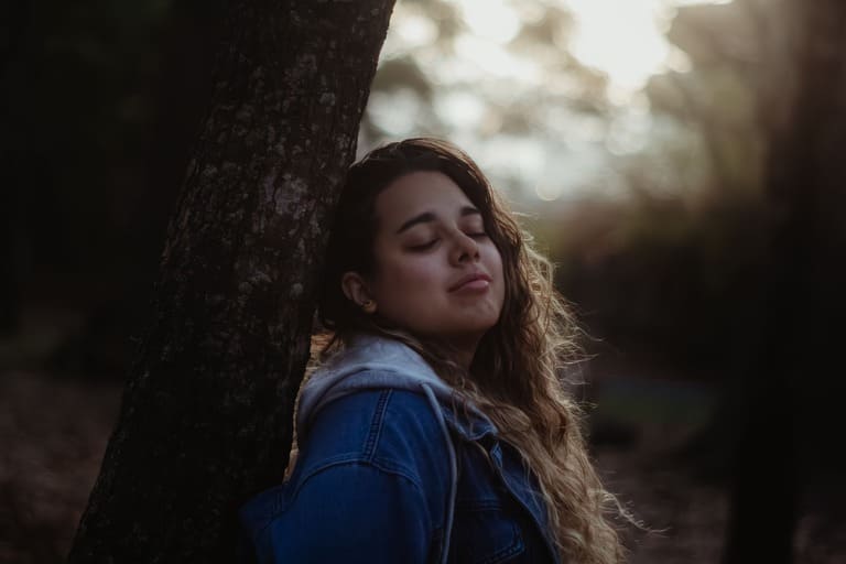 Femme les yeux fermés appuyée contre un arbre – gestion du stress par l'hypnose et sophrologie avec Marie Adeler à Châtillon
