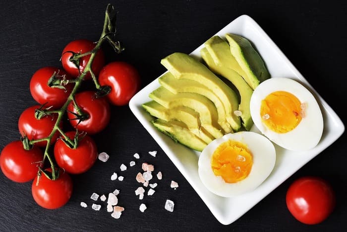 Assiette composée d'avocat, d'œufs durs et de tomates pour adopter une alimentation équilibrée après l'arrêt du tabac