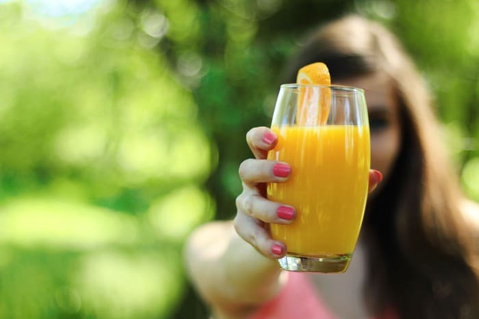 Personne tenant un verre de jus d'orange pour favoriser une bonne hydratation après l'arrêt du tabac