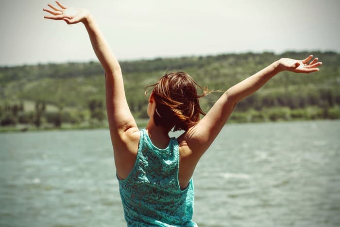Femme respirant profondément au bord de l'eau pour retrouver calme et sérénité