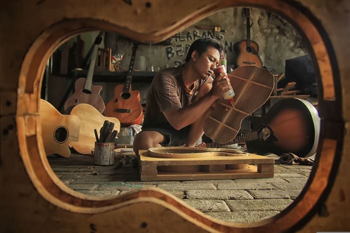 Une personne fabrique une guitare dans un atelier, illustrant l'importance de prendre du temps pour soi à travers une activité créative et apaisante.