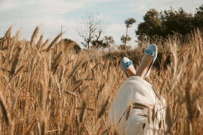 Femme allongée dans un champ de blé profitant d’un moment de calme et de détente