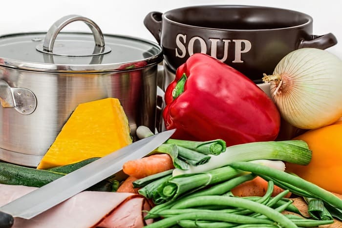 Des légumes frais, une casserole et des ingrédients de cuisine illustrent l'importance d'une alimentation saine pour prendre soin de soi au quotidien.