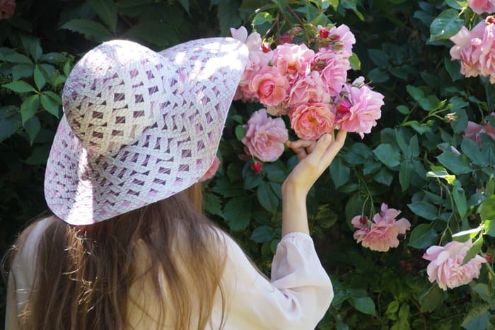 Une personne contemple et touche délicatement des roses dans un jardin, symbole du bien-être, de la sérénité et du fait de prendre soin de soi sans culpabilité.