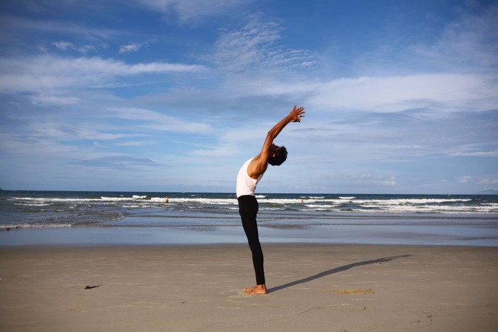 Personne en étirement face à la mer illustrant le retour au corps et l’apaisement du mental