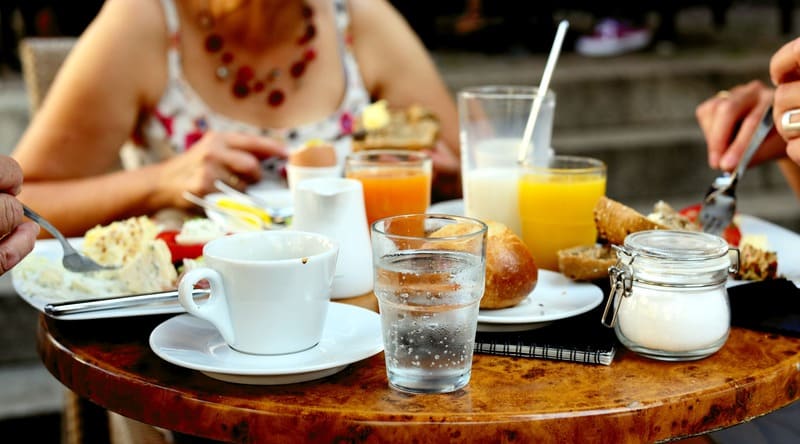 Petit-déjeuner partagé autour d'une table avec boissons, pain et assiettes garnies