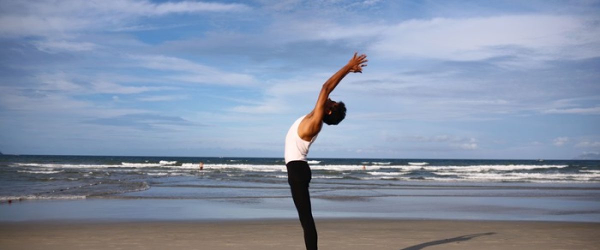 Personne en étirement face à la mer illustrant le retour au corps et l’apaisement du mental