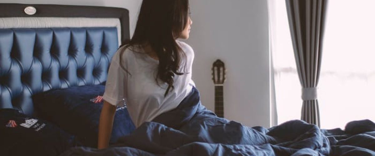 Personne assise sur son lit au réveil dans une chambre calme favorisant un sommeil réparateur