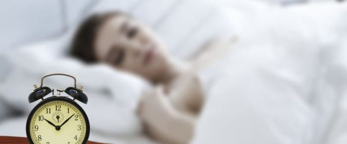 Réveil près du lit illustrant la rumination mentale le soir et les difficultés à apaiser ses pensées avant de dormir